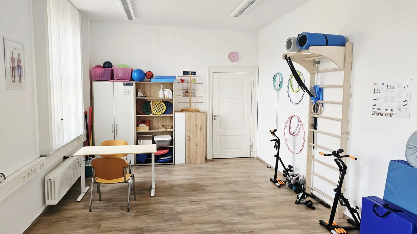 Therapieraum mit Sprossenwand, Bewegungsgeräten und Arbeitstisch